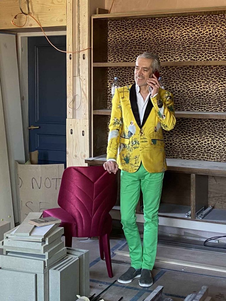 Top London interior designer in Yellow blazer and green trousers in study
