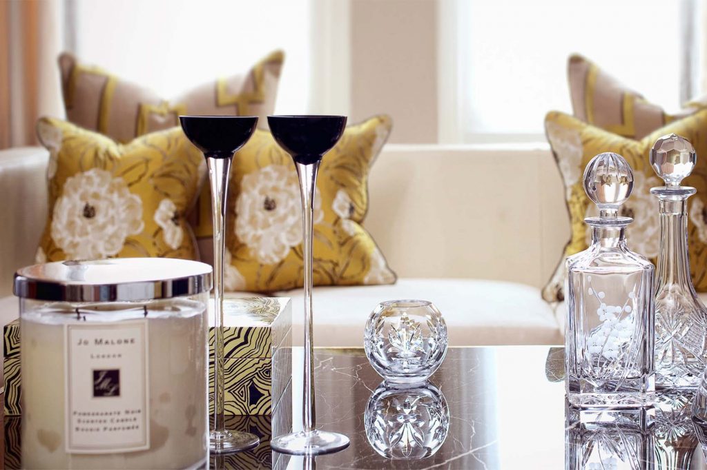 A curated group of table accessories and decanters along with silk sofa scatter cushions