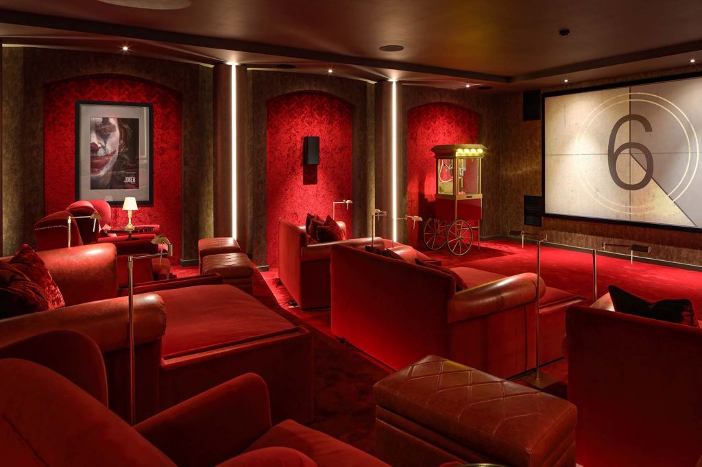 Large red cinema room with velvet walls and luxurious two seat sofas