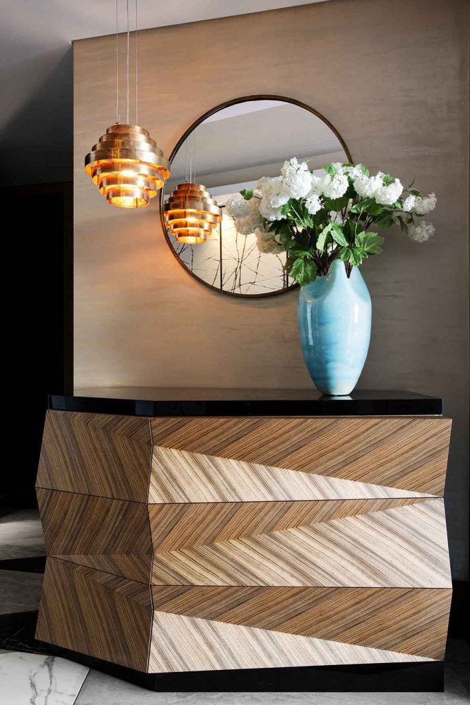 Angular Zebrano drawer unit set against a polished plaster background and copper pendant
