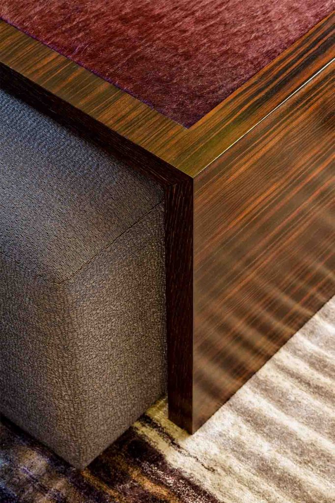 Detail of leather upholstered coffee table in Macassar ebony with linen ottoman and silk rug