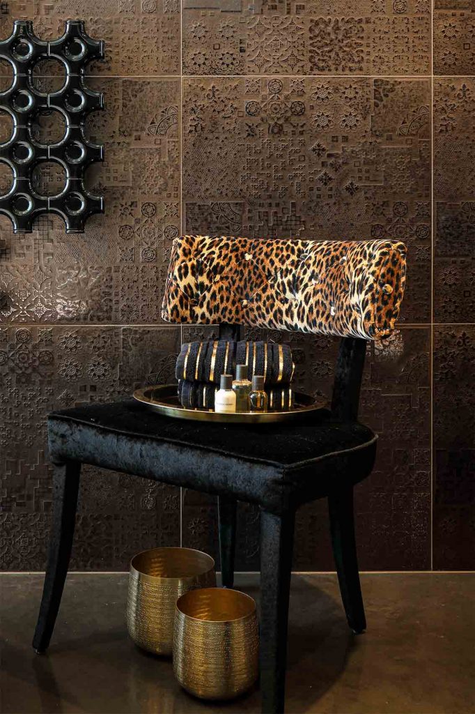 Rose gold ceramic bathroom wall tiles, leopard velvet chair, gold accessories