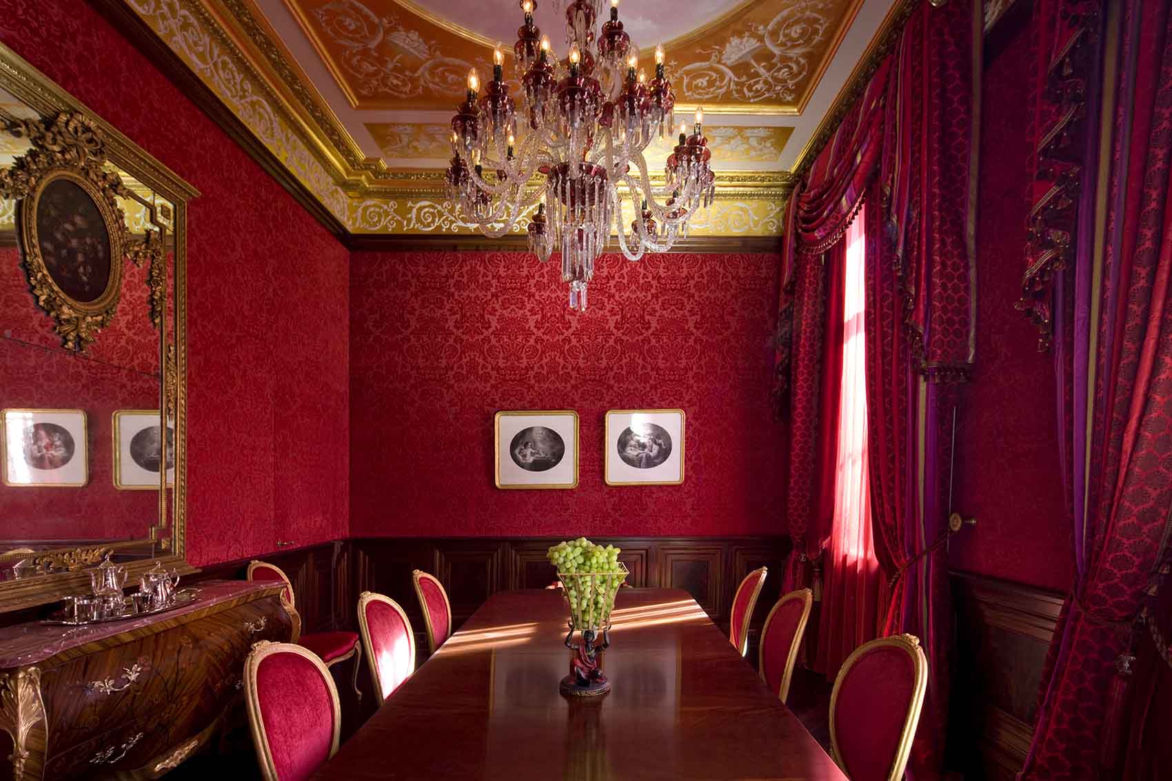 Dining room design, red velvet walls, red silk curtains and tie backs, mahogany dining table