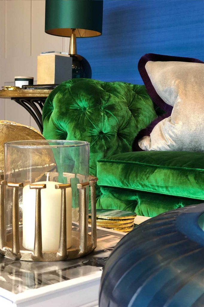 Emerald green silk velvet sofa, cornflower blue silk wall covering, glass accessories