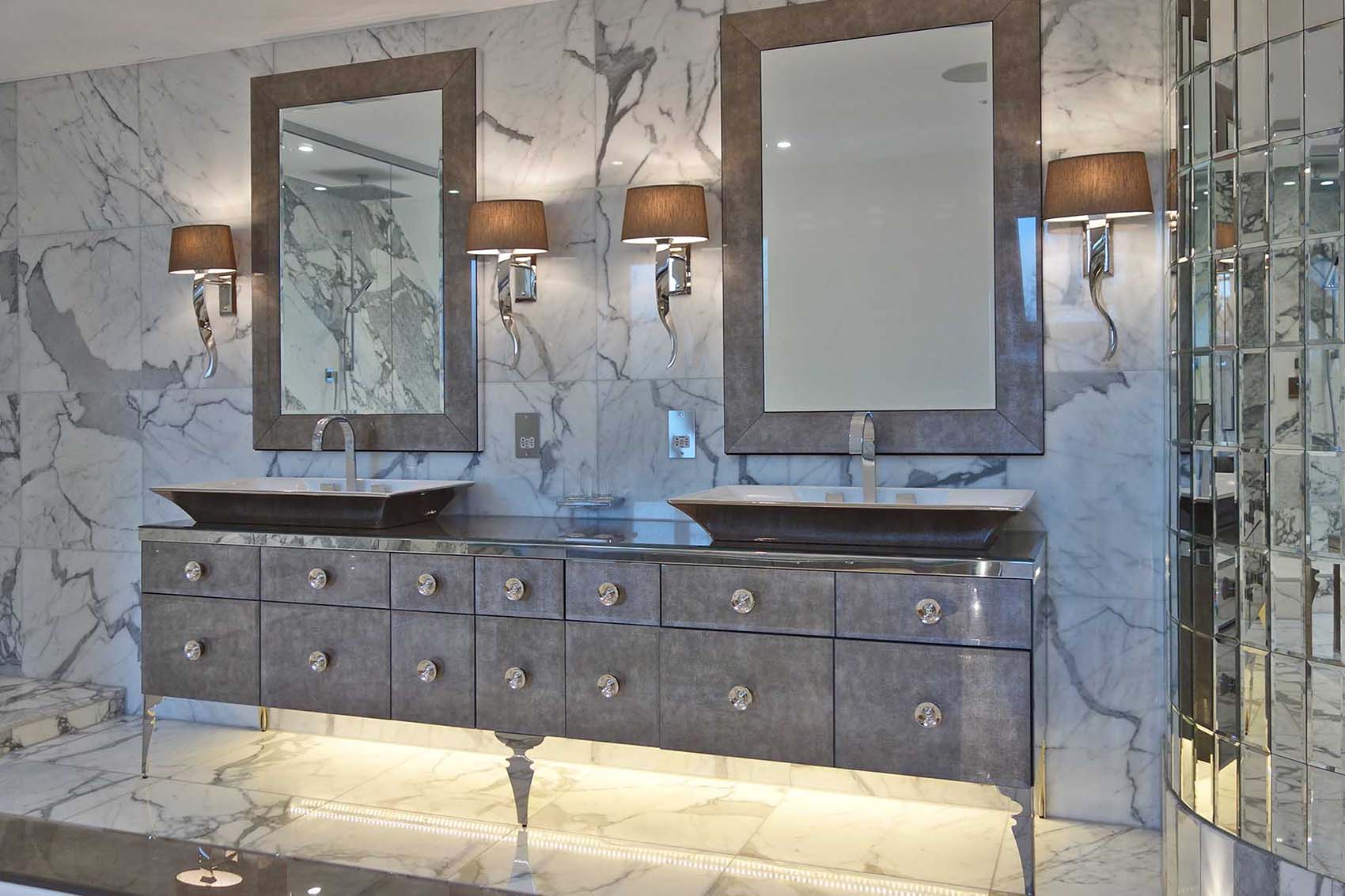 Master bathroom with marble floor and walls, chrome wall lights with silk shades