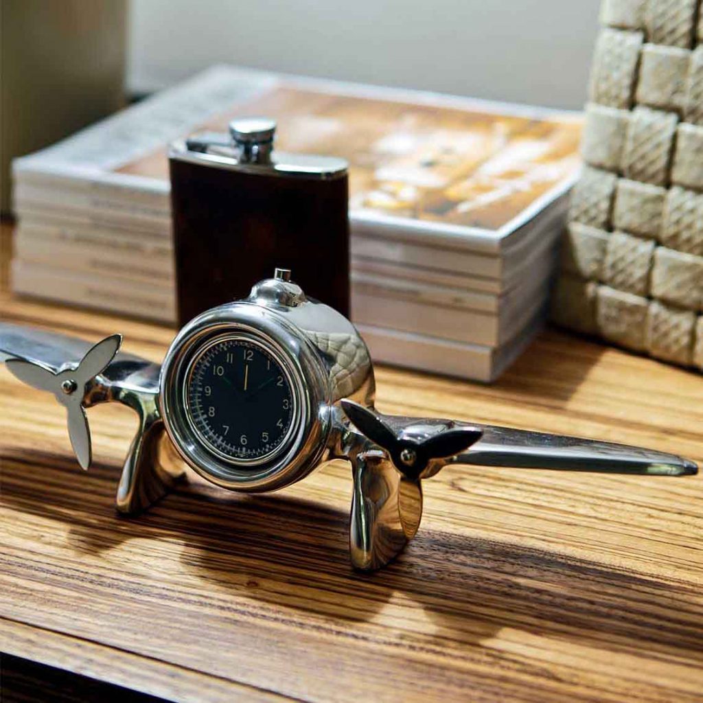 Vignette with aeroplane chrome clock, hip flask in leather, interior magazines