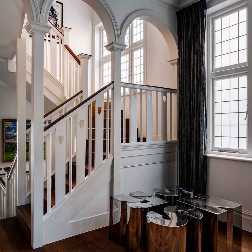 Staircase design with arches, chrome letter stools, linen curtains, timber floor, white walls