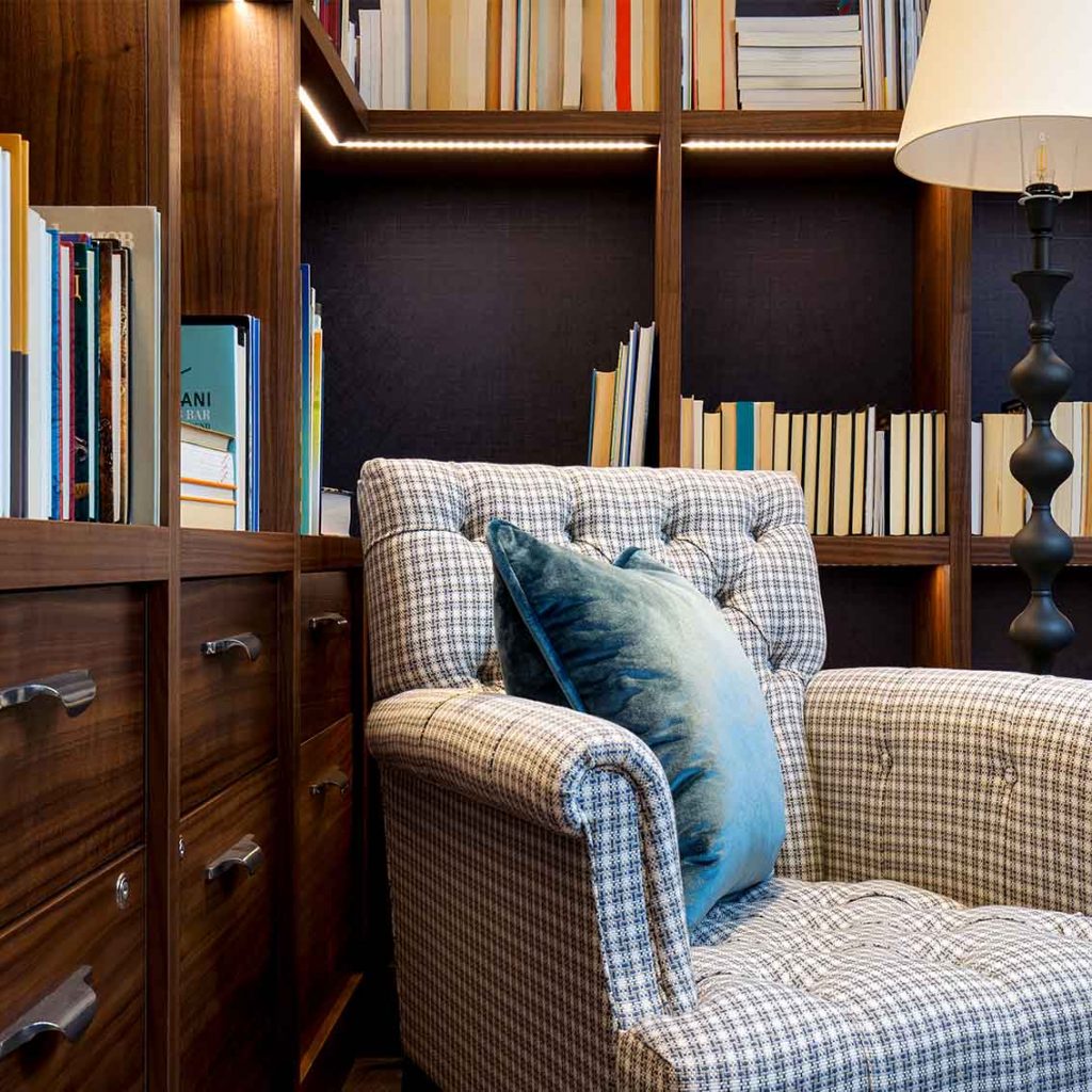 Plaid upholstered arm chair, blue silk velvet cushion, walnut book shelves