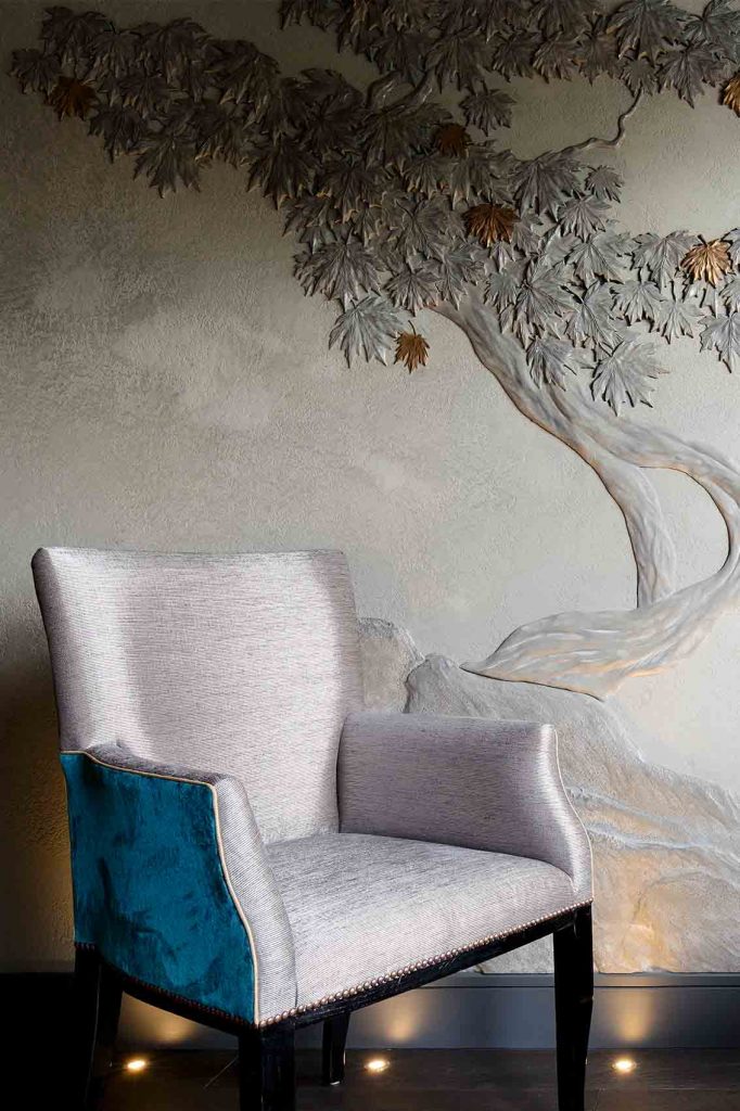 Grey polished plaster wall with bonsai bas relief in silver and gold