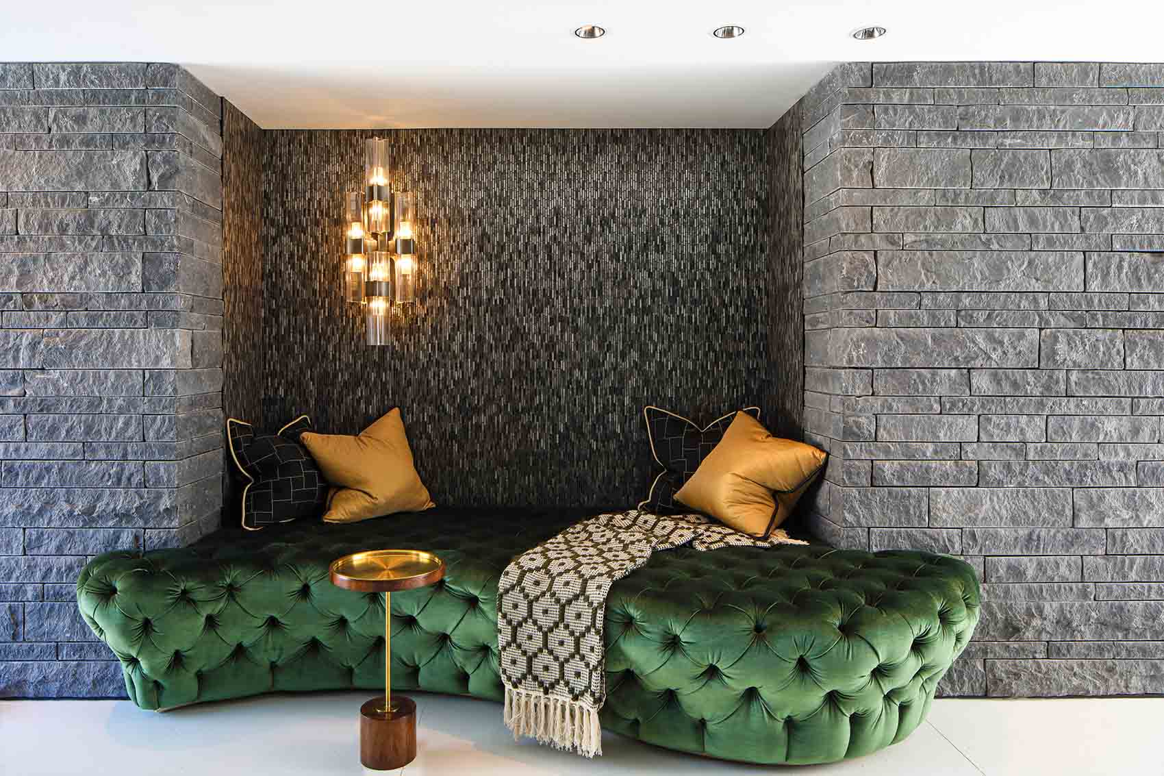Curvaceous deep buttoned banquette in green velvet with gold scatter cushions and crystal light