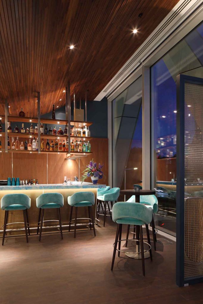 Turquoise velvet bar chairs, polished walnut panels, edge lit bar counter